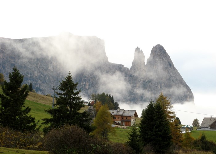Mountain peaks shrouded in fog with houses and trees in Italy