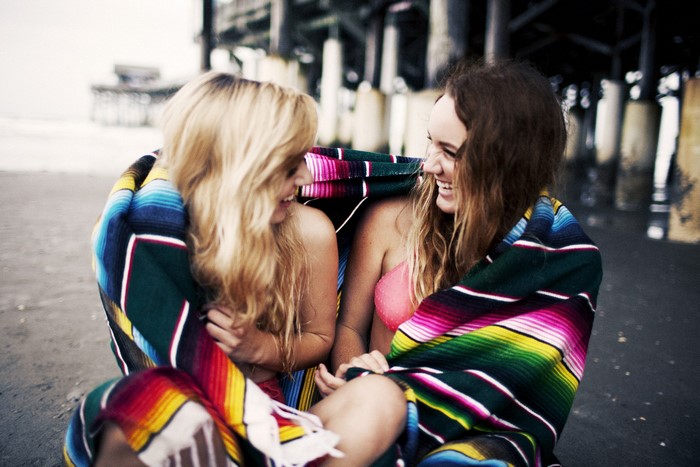 Two girls wrapped in a blanket on a beach