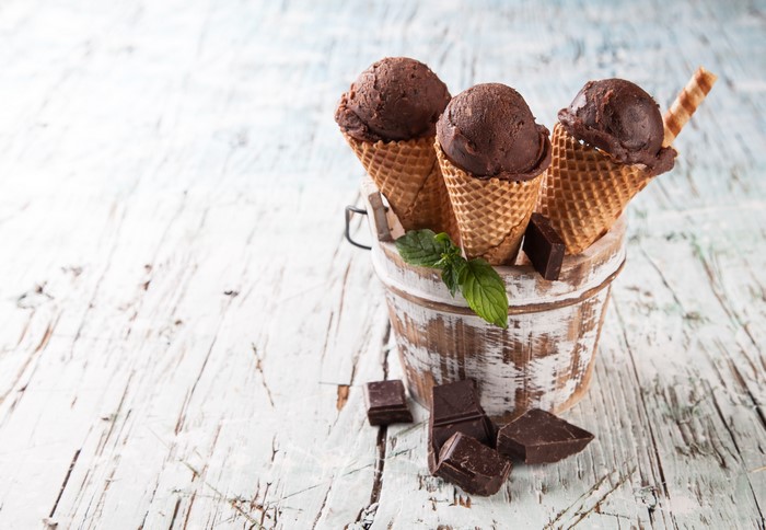 Three chocolate ice cream cones in a bucket with chocolate chunks