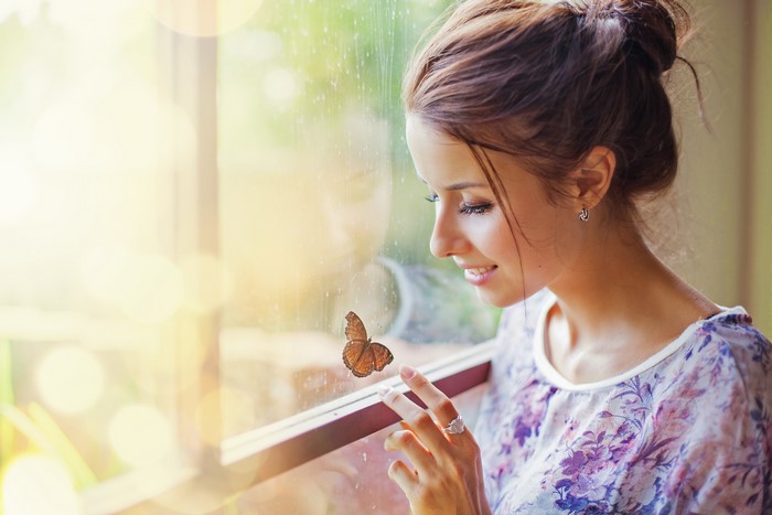 Woman looking at a butterfly on a window