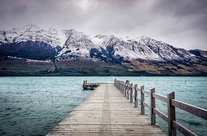Wooden pier on a lake with snow-capped mountains in Glenorchy, New Zealand