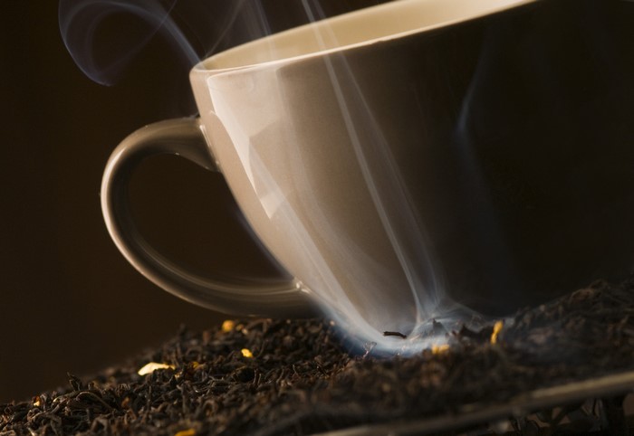 Cup of hot tea with smoke and tea leaves