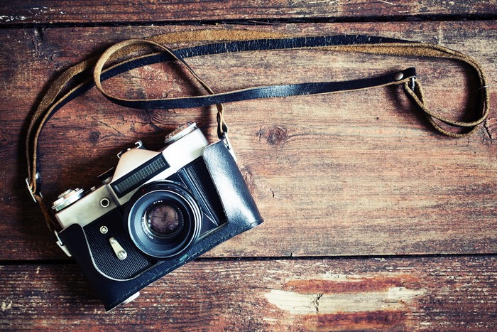 Vintage camera with leather strap on wooden background