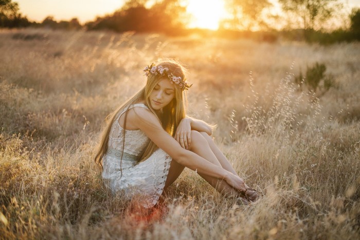 Girl with flower crown in a field at sunset