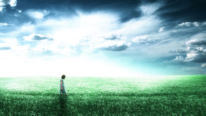 Little girl in a field under a cloudy sky