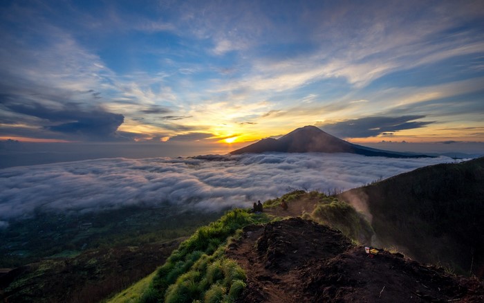 Sunrise over mountains with clouds and two people