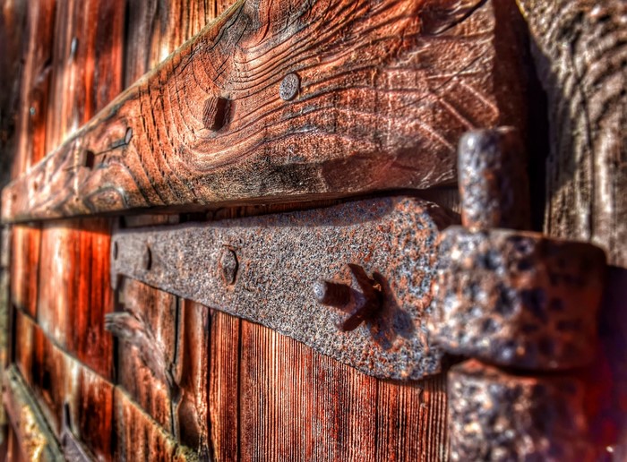 Close-up of rusty hinges on a wooden door