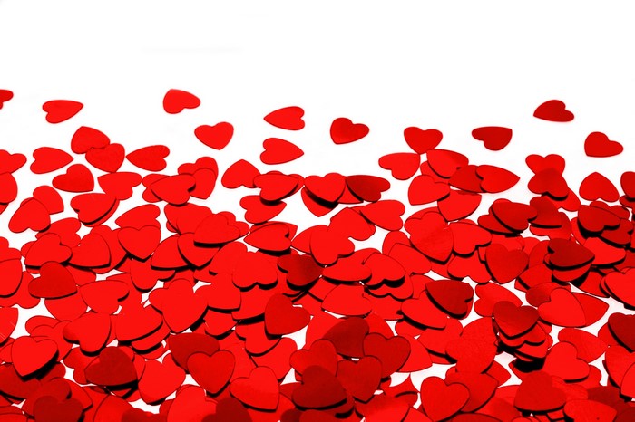 Scattered red heart confetti on a white background