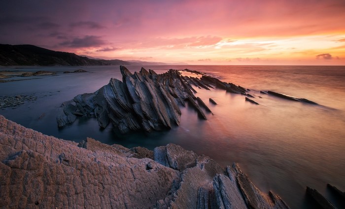 Jagged rock formations in the sea at sunset
