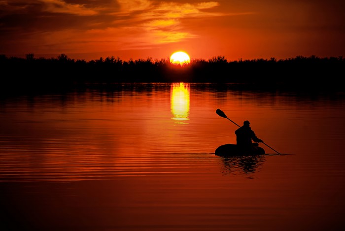 Man in Boat on Lake at Sunset