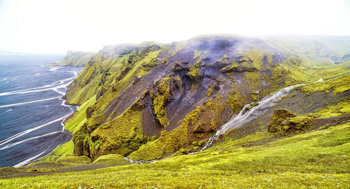Mossy Cliffs Overlooking a Black Sand River Delta