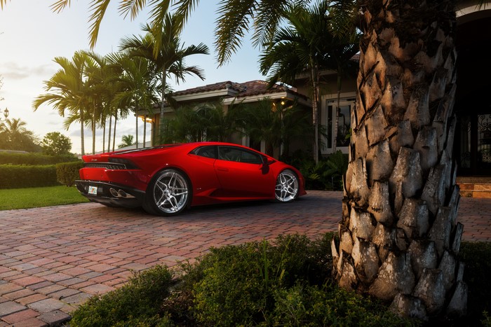 Red Lamborghini Huracan parked in front of a house with palm trees