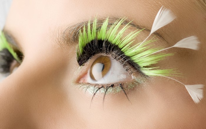 Close-up of a woman's eye with green and white feathered eyelashes