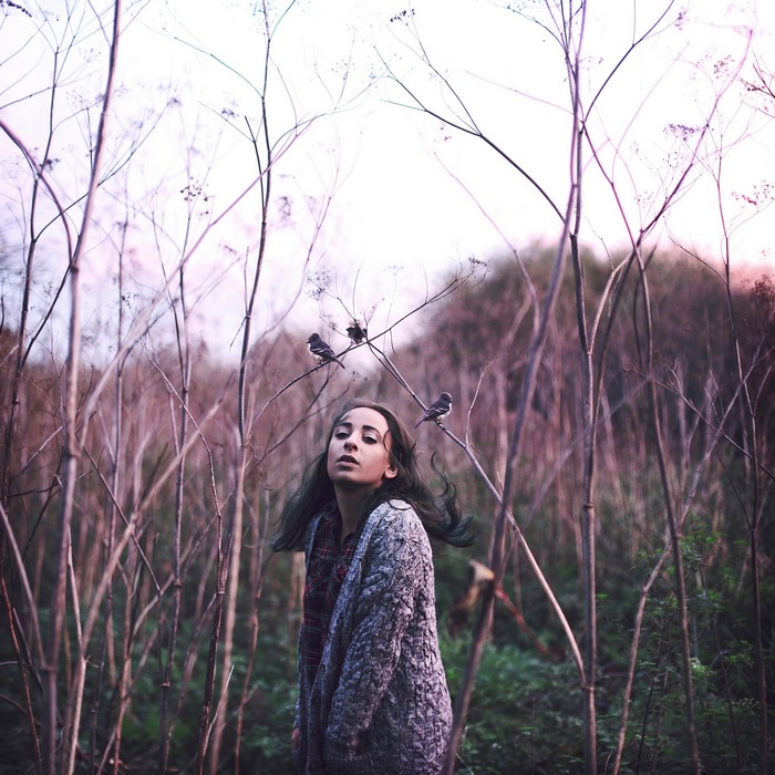 Girl with birds on branches in a forest
