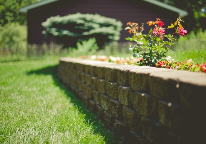 Stone retaining wall with flowers and grass