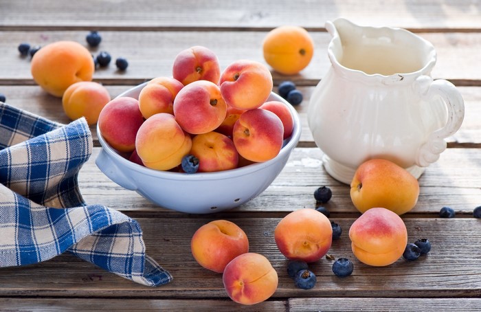 Apricots and blueberries in a bowl with a pitcher