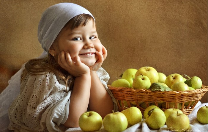 Little girl with apples in a wicker basket