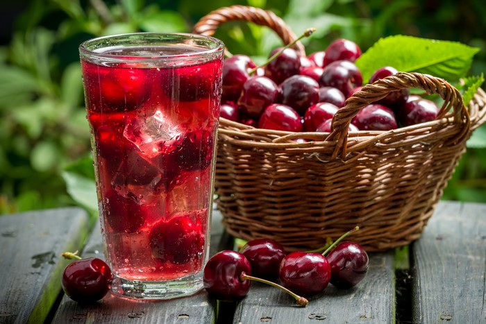 Cherries in a basket and a glass of cherry drink with ice