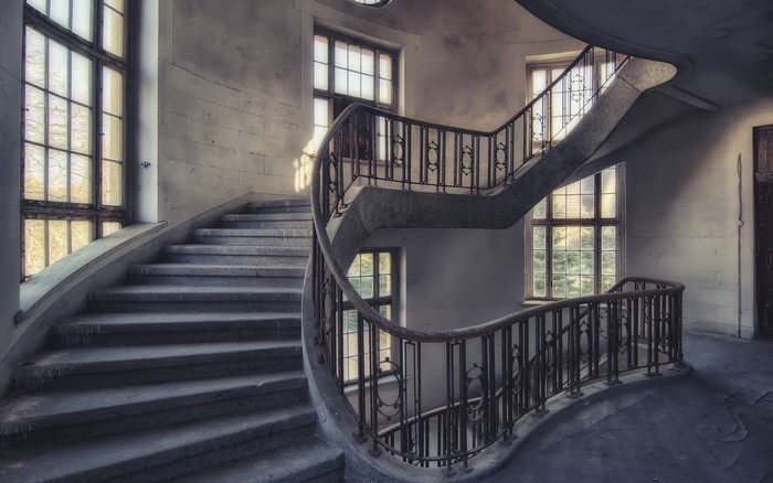 Abandoned building interior with spiral staircase and windows