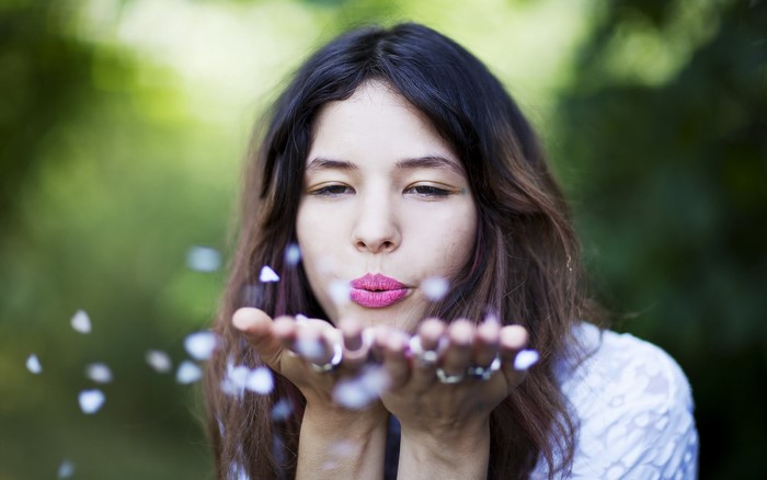 Woman blowing petals from her hands