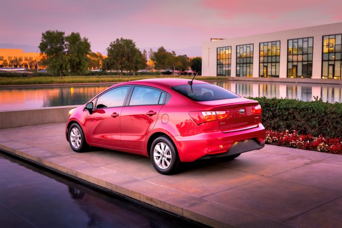 Red 2016 Kia Rio SX sedan parked by a building