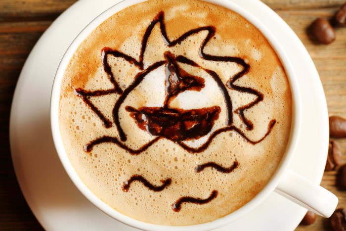 Coffee with chocolate art of a sailboat and sun