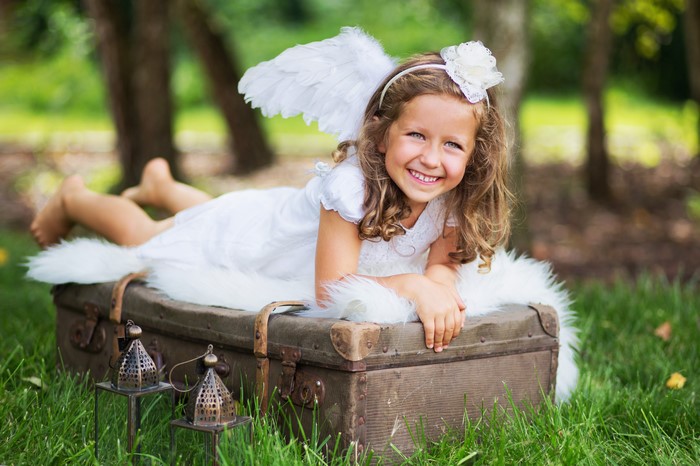 Little girl with angel wings on a suitcase