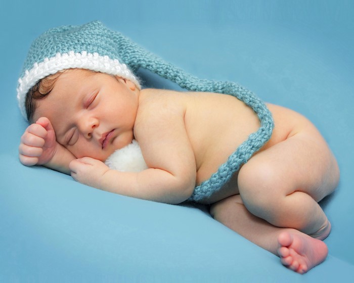 Newborn baby sleeping in a blue knitted hat