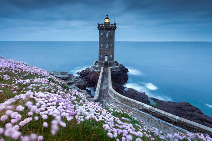 Lighthouse on a rocky coast with flowers