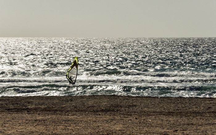 Windsurfer on the sea with a beach in the foreground