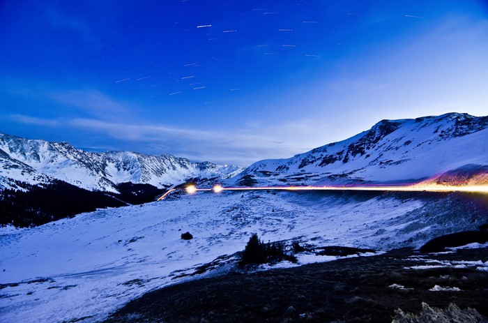 Snowy Mountains at Night with Star Trails and Car Lights