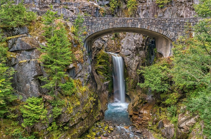 Stone bridge over a waterfall in a rocky gorge