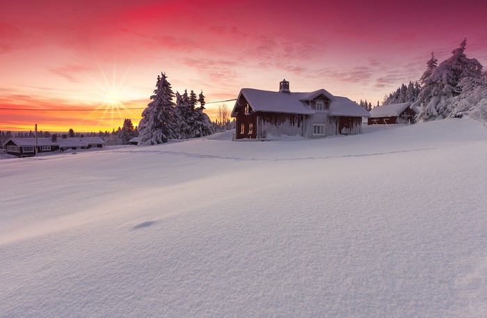 Snowy houses at sunset with sun rays
