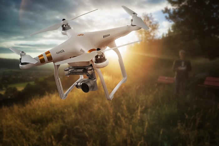 DJI Phantom drone flying over a field at sunset