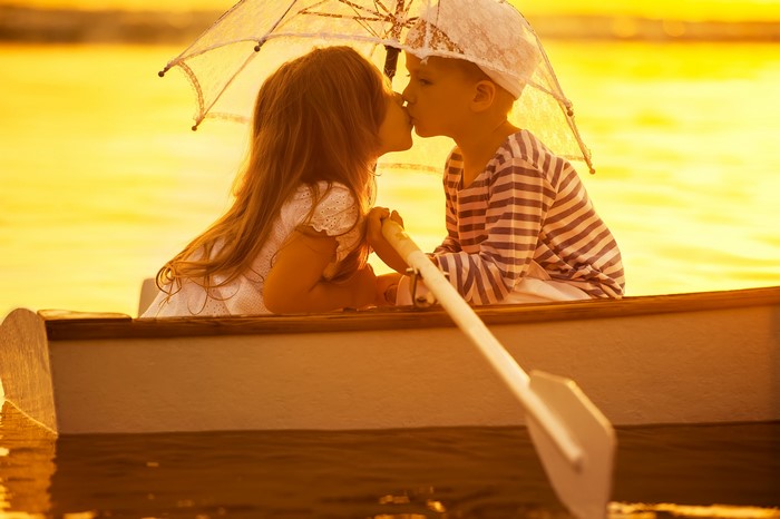 Two children kissing in a boat under an umbrella