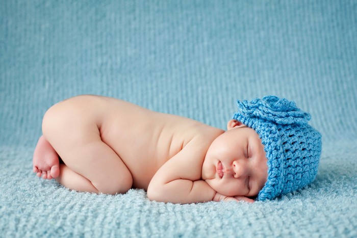 Newborn baby sleeping in a blue hat