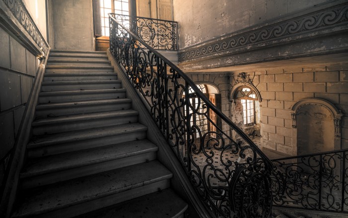 Abandoned grand staircase with ornate railing