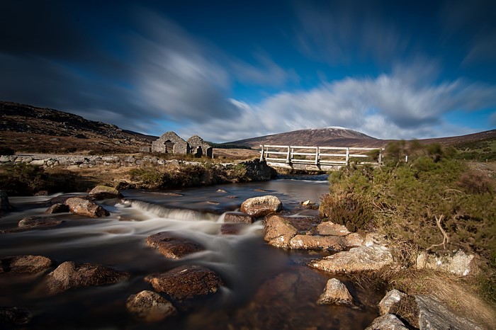 Ruins and bridge over a river with a mountain in the background