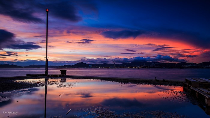 Sunset over water with reflection and pier light