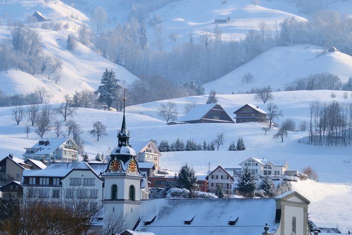Snowy village with church tower and mountains
