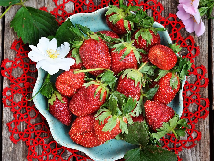 Strawberries in a blue bowl with flowers