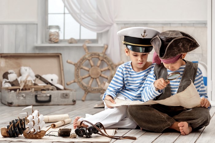 Two boys dressed as sailors and pirates looking at a map