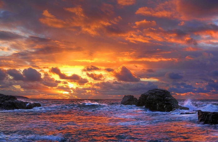 Sunset over the sea with waves and rocks