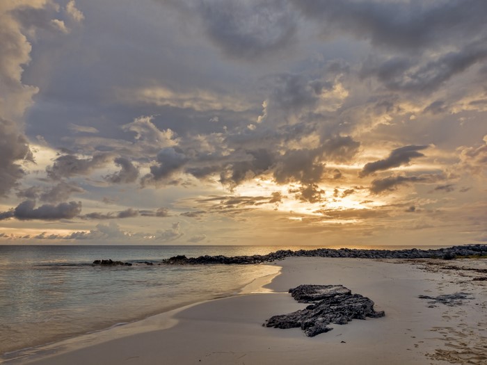 Beach with rocks and cloudy sunset sky