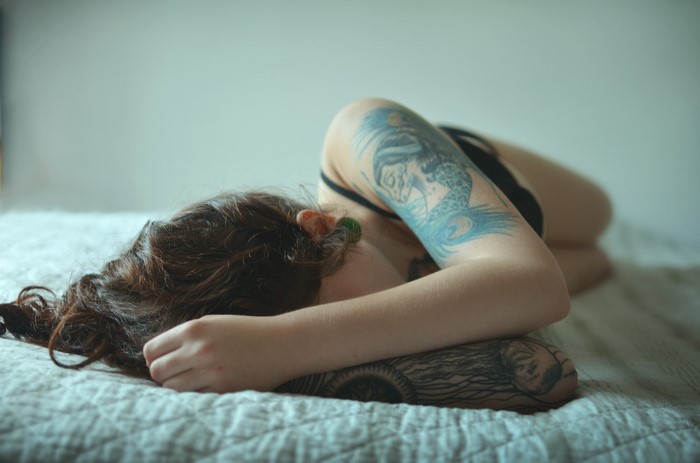 Woman with tattoos sleeping on a bed