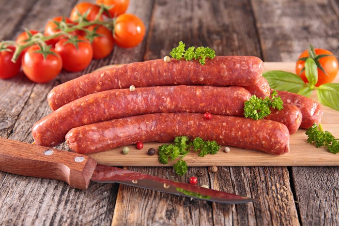 Raw sausages with tomatoes and a knife