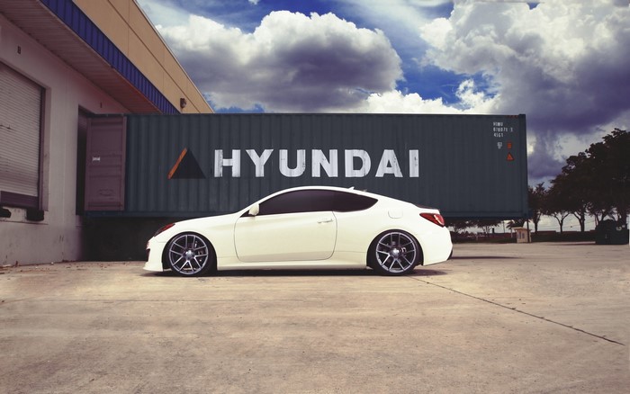 White Hyundai Genesis Coupe parked by a shipping container