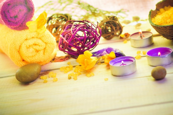 Spa setting with rolled towels, candles, and bath salts