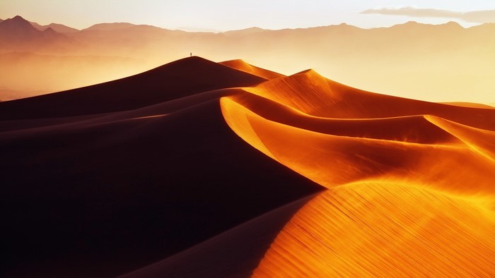 Desert dunes at sunset with mountains in the background