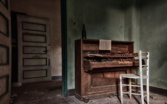 Abandoned room with a broken piano and chair